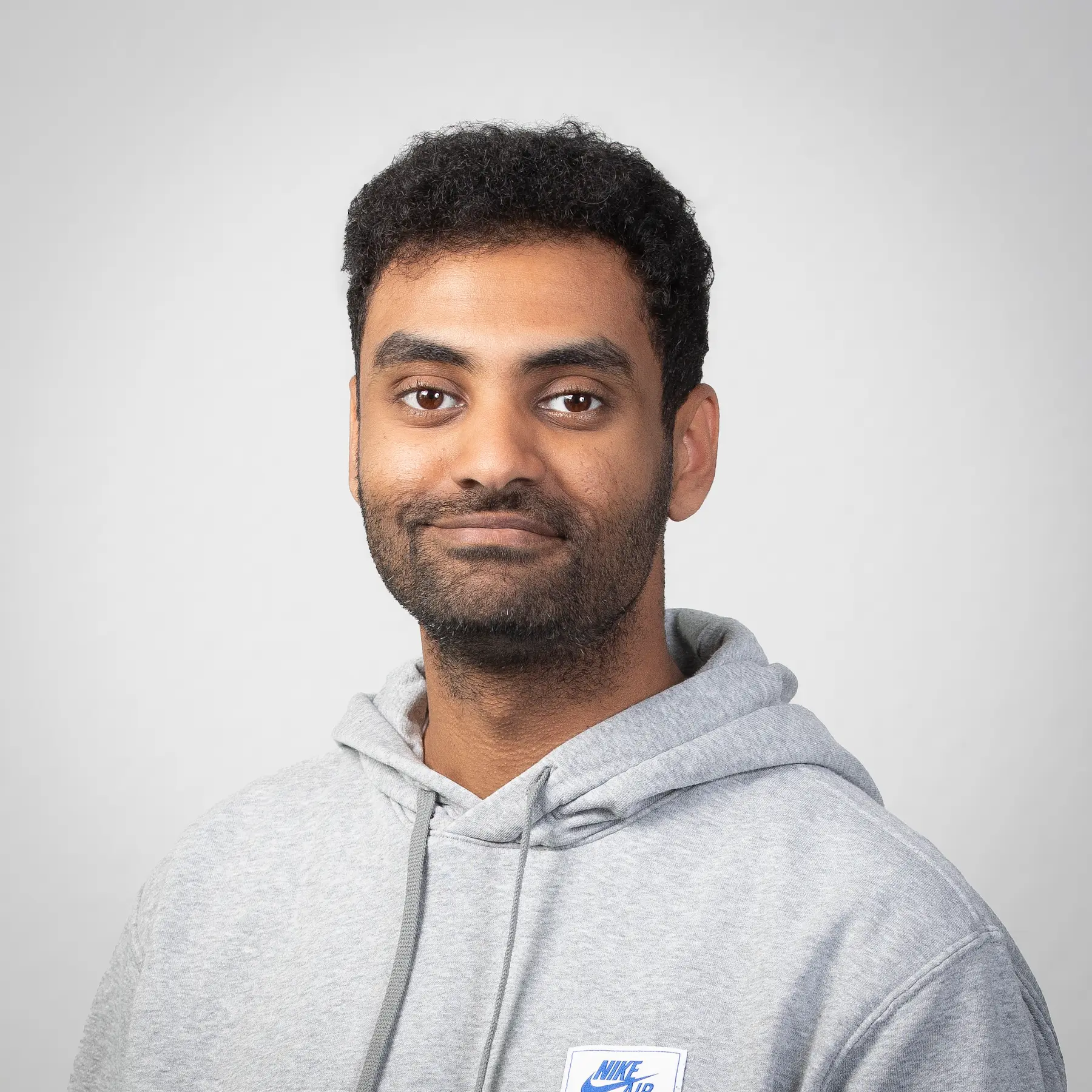 Ishak Kindane posiert für ein professionelles Portraitfoto vor einem hellen Hintergrund.