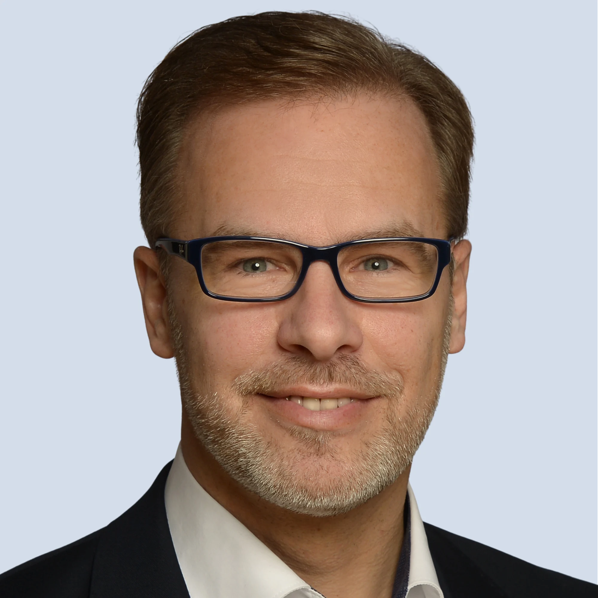 LSB_Hauptausschuss_Alexander Svoboda Alexander Svoboda lächelt in die Kamera, trägt Brille, Portrait vor einem hellblauen Hintergrund