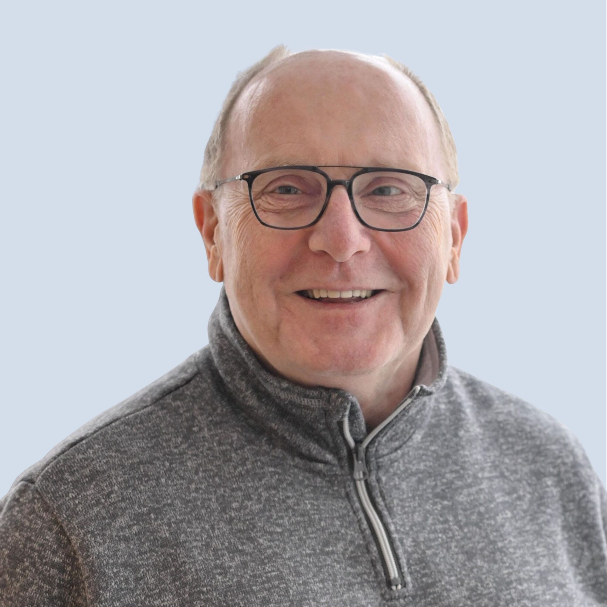 LSB_Hauptausschuss_Axel_Zielinski Axel Zielinski lächelt in die Kamera, trägt Brille, Portrait vor einem hellblauen Hintergrund
