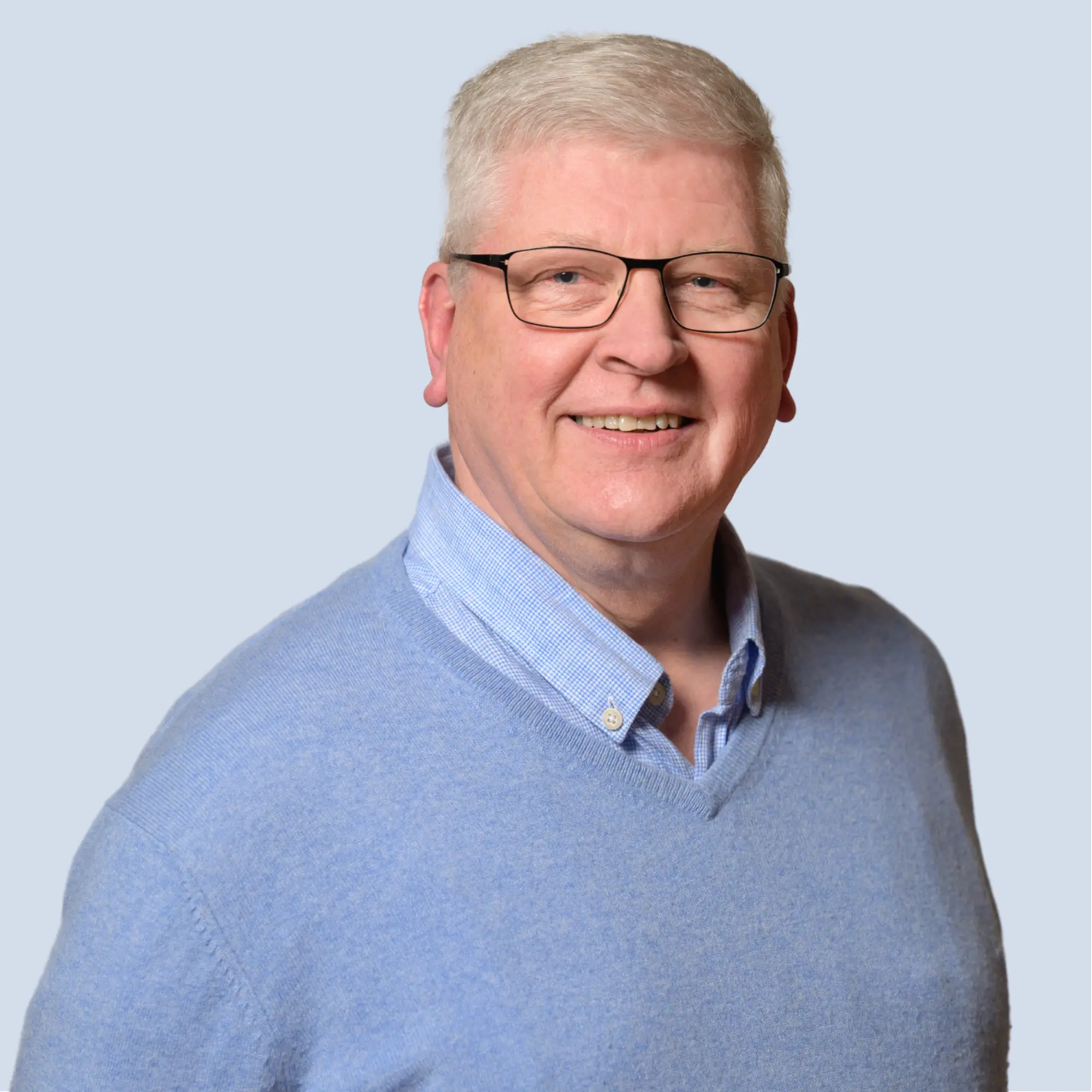 LSB_Hauptausschuss_Christian_Stubbe Christian Stubbe lächelt in die Kamera, trägt Brille, Portrait vor einem hellblauen Hintergrund