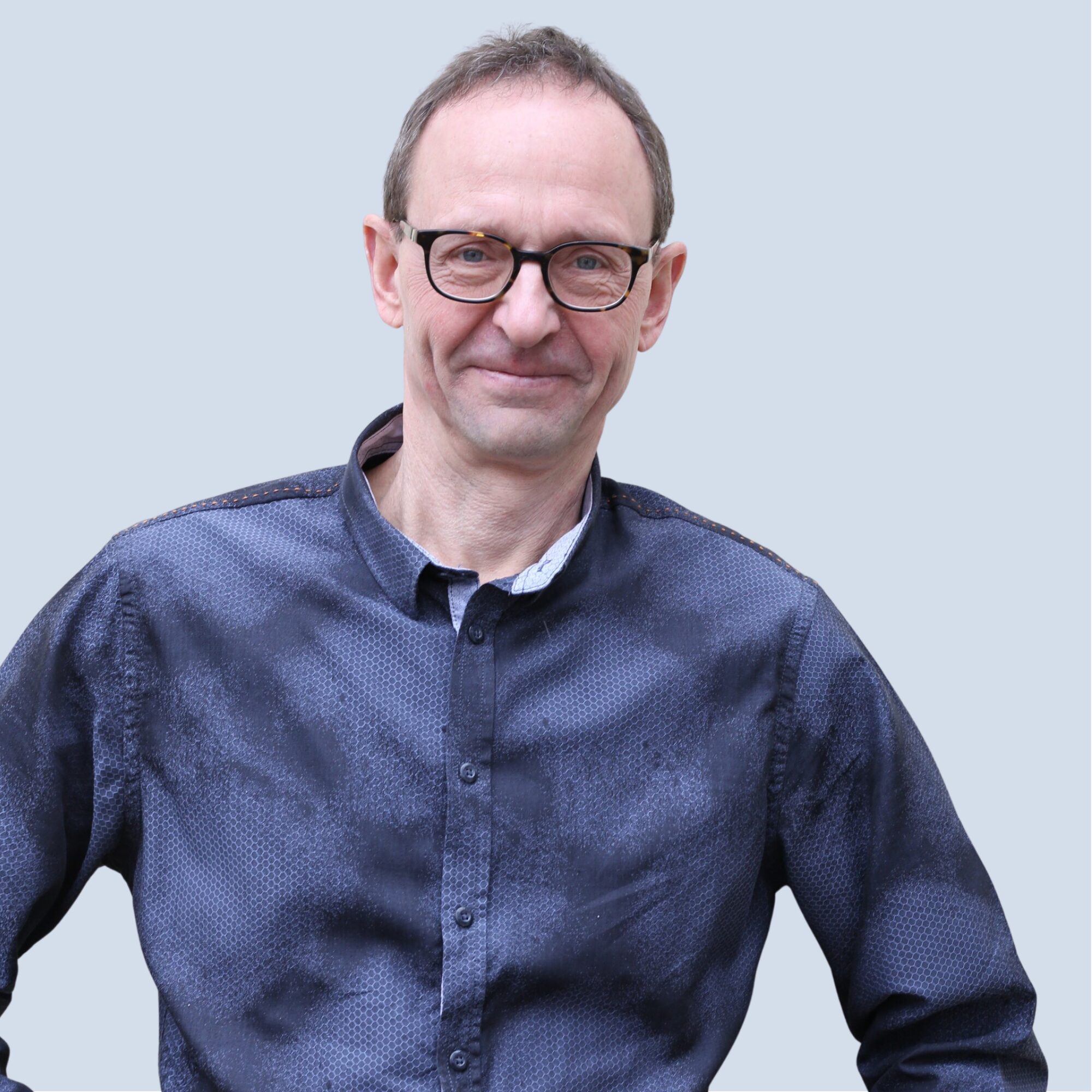 LSB_Hauptausschuss_Ewald_Dankwardt Ewald Dankwardt lächelt in die Kamera, trägt eine Brille, Portrait vor einem hellblauen Hintergrund