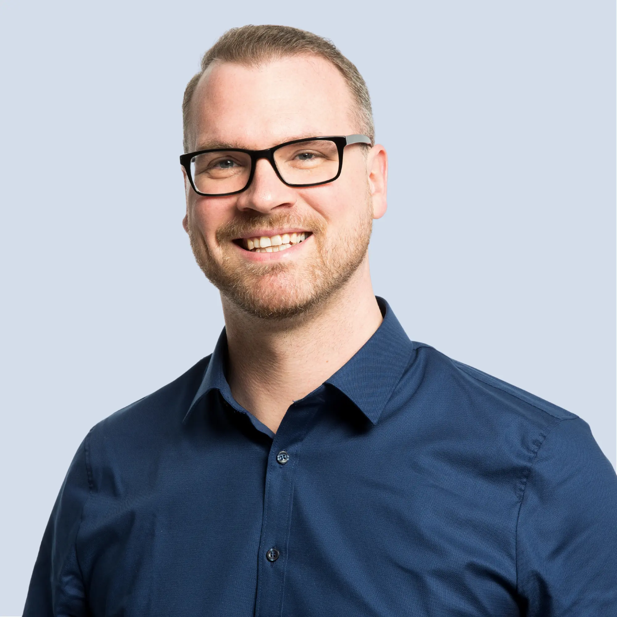 LSB_Hauptausschuss_Sebastian_Stern Sebastian Stern lächelt in die Kamera, trägt Brille, Portrait vor einem hellblauen Hintergrund
