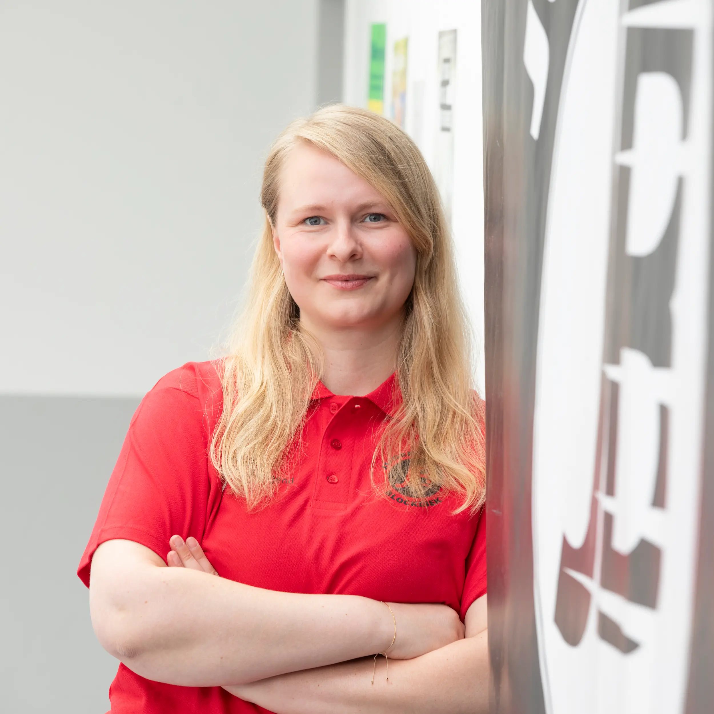 Svenja Dietz posiert für ein professionelles Portraitfoto vor einem hellen Hintergrund mit dem Logo des Jugendtreffs Blockdiek.